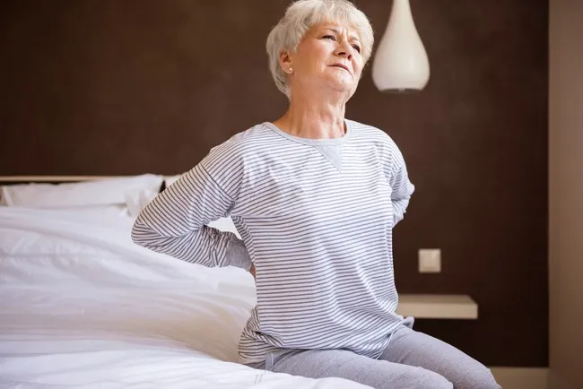 Mulher com dor sentada na cama